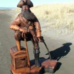 Cedar Sculpture of Pirate with Peg Leg and Treasure Chest Shown on the Beach at a Height of 4ft
